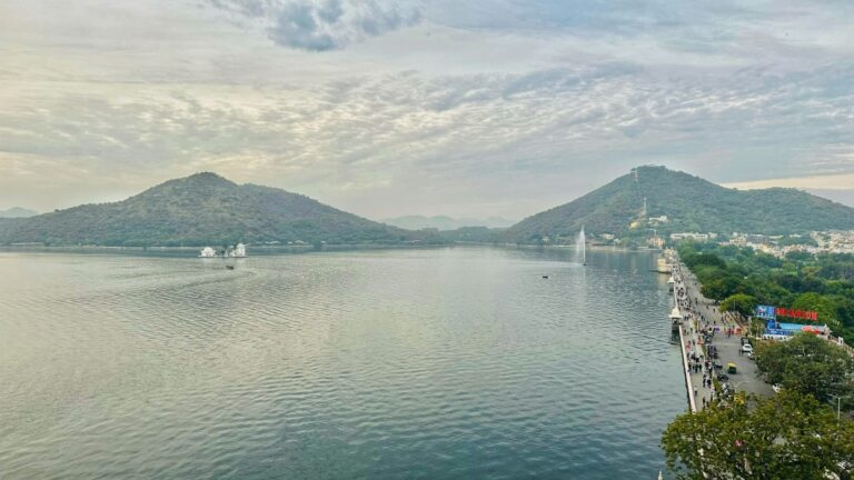 Serene view of Fateh Sagar Lake in Udaipur, India, surrounded by lush green hills.