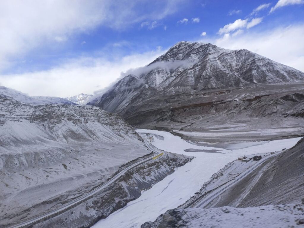 the frozen Zanskar River during the Chadar Trek in Ladakh, surrounded by towering cliffs and snow-covered landscapes.