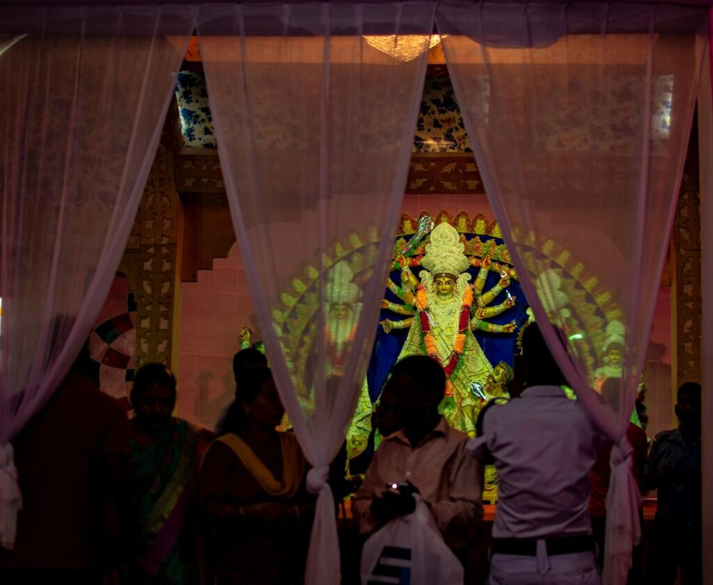 Devotees offering prayers and lighting incense in front of the Durga idol during the Durga Puja festival.