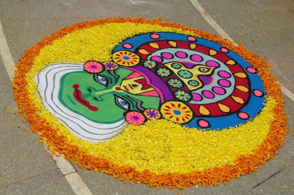 the face of a kathakali dancer portrayed on the ground using flower petals and colored rice flour during Onam festival celebrations.