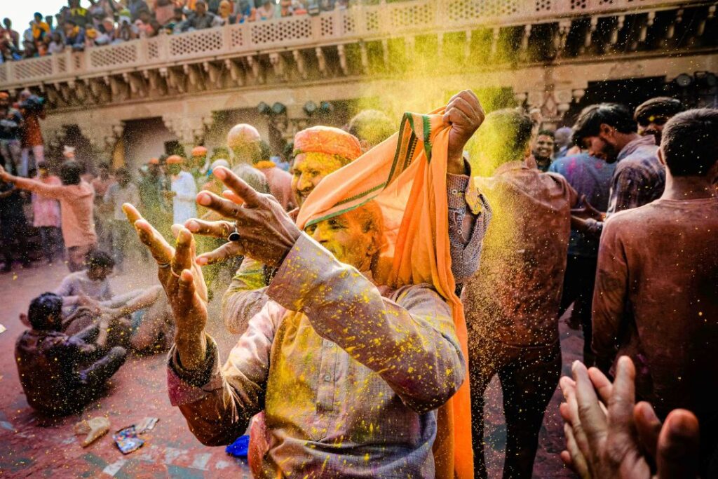 Close-up of hands covered in bright hues of pink, blue, and yellow during the Holi festival.