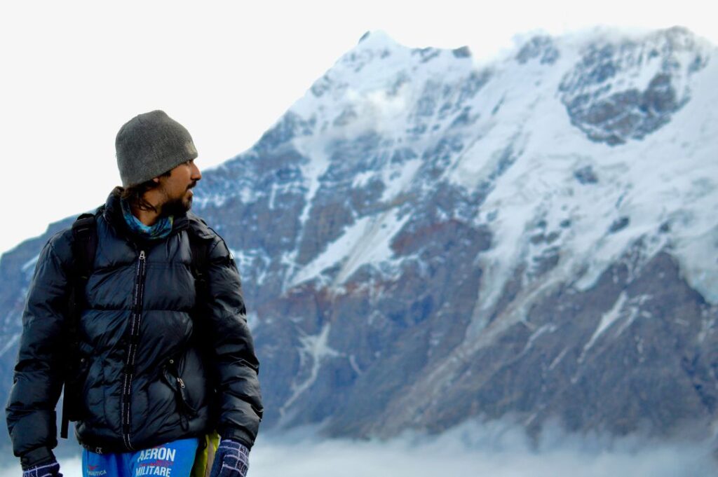 Adventurer standing in front of snow-capped peaks on the Roopkund Trek.